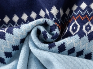 Macro detail of blue knit fabric with geometric diamond and wavy jacquard patterns