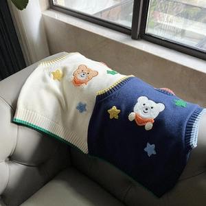 Detail of children's knit vests featuring 3D bear embroidery and colorful star patches