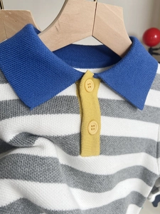 Detail of striped knitted polo sweater for boys featuring a contrast collar and button placket