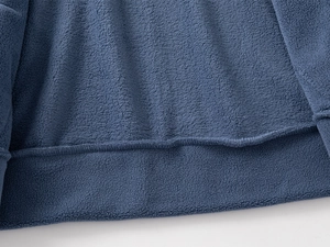 Vue macro détaillée de la texture polaire gris-bleu et des coutures lisses sur l'ourlet