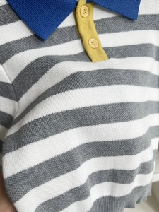 Detail of knit polo sweater showing grey stripes and contrasting yellow button placket