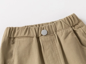 Detailed close-up of khaki cotton boy's casual pants with elastic waistband and metal button
