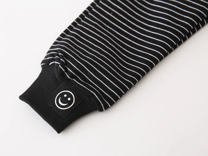 Detail of boys' striped joggers featuring ribbed cuffs and a smiley face embroidery patch