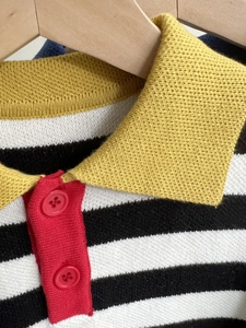 Detail of color-block knit polo shirt collar with red buttons and black white stripes