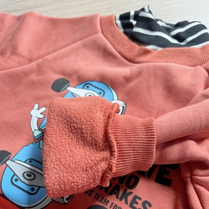 Détail du sweat-shirt enfant rose saumon avec doublure polaire chaude et motif skateboard