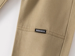 Detail of khaki twill cotton trousers with black FASHION woven label and fine stitching