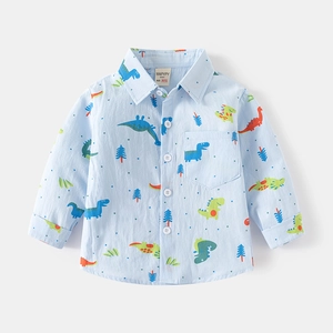 Dettaglio di una camicia da bambino azzurra in cotone con stampe di dinosauri colorati