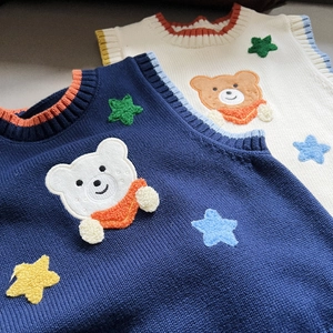 Close-up of knit vest featuring embroidery bear pattern and ribbed striped neckline