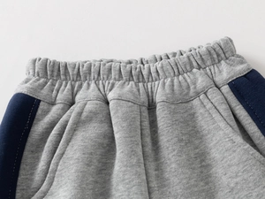 Detail of grey boys sports pants with elastic waistband and navy side stripes