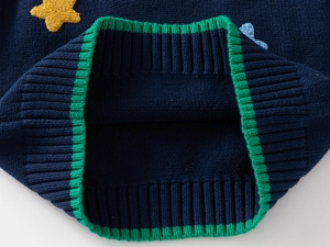 Macro shot of knitted star embroidery and green ribbed trim on kids vest