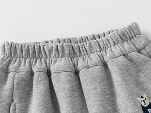 Close-up of kids grey fleece joggers featuring elastic waist and cute bear embroidery