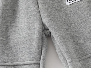 Detailed macro shot of reinforced crotch stitching and SPORT label on gray toddler pants