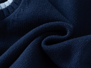 Macro detail of navy knit vest with fine flat stitching and contrast ribbed neckline