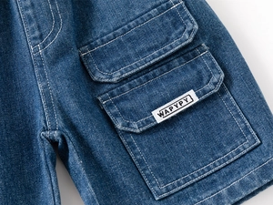 Detail of cargo pocket with brand tag on dark blue denim shorts for boys