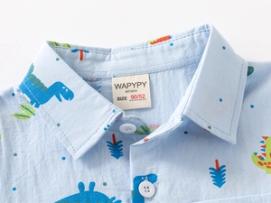 Dettaglio colletto camicia bambino con stampa dinosauro e bottone bianco in cotone