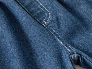 Macro shot of dark blue denim fabric showing detailed white contrast double stitching