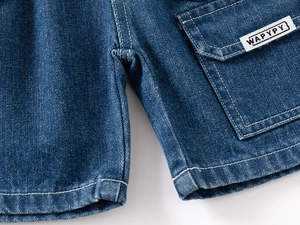 Detail of blue denim shorts showing white contrast stitching and a woven logo label