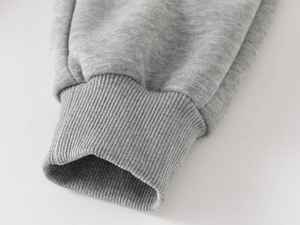 Close-up of gray fleece trousers showing the elastic ribbed cuffs and soft inner lining