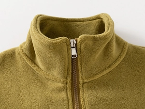 Detail shot of a mustard yellow polar fleece jacket with a high collar and metal zipper