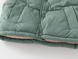 Detail of sage green quilted kids vest with warm fleece lining and resin buttons
