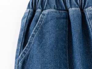 Detail of boys denim shorts showing elastic waistband and reinforced white stitching