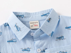Close-up of the collar and light blue cotton fabric with cartoon truck prints on the shirt