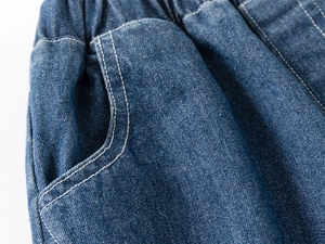 Detail of boys denim shorts showing elastic waistband and curved pockets with white stitching