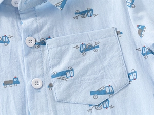 Detailed close-up of cartoon car prints and chest pocket on a blue cotton boy shirt