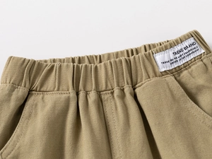 Detail of khaki kids' trousers featuring elastic waistband and trend brand woven label
