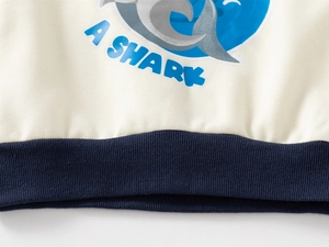 Détail de l'ourlet côtelé sur un sweat en coton blanc cassé avec imprimé requin