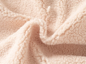 Close-up of warm beige thick faux shearling fabric texture for children winter vest