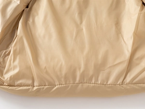 Close-up of the smooth khaki polyester lining and fine stitching of the boy's winter vest