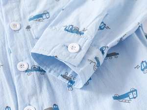 Close-up of boys long sleeve blue shirt featuring cartoon truck prints and cotton texture