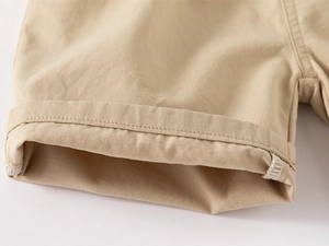 Dettaglio ravvicinato dell'orlo risvoltato su pantaloncini in twill di cotone kaki con cuciture