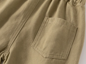 Detailed macro view of khaki cotton twill pants with precise stitching and a rear patch pocket