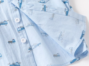 Close-up of light blue cotton boy's shirt with cartoon truck print and button detail
