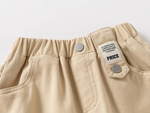 Detail of elastic waist and white woven label on khaki casual pants for boys
