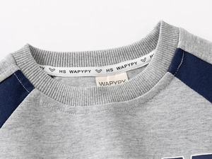 Detailed close-up of crew neck stitching and brand label on a kids' sportswear sweatshirt