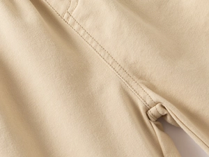 Detail of double-needle stitching and twill cotton texture on beige boys' leisure pants
