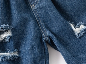 Vue rapprochée d'un short en jean bleu avec déchirures usées et détails d'ourlets effilochés