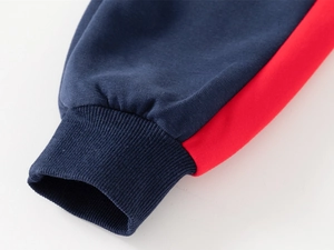 Détail macro de poignets côtelés bleu marine avec bandes rouges sur vêtement sport enfant