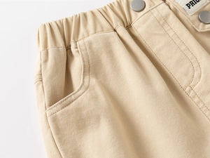 Detail of elastic waistband and beige twill fabric with side pockets on kids trousers