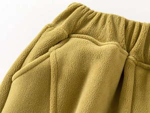 Detail of mustard yellow fleece kids pants showing elastic waist and soft texture