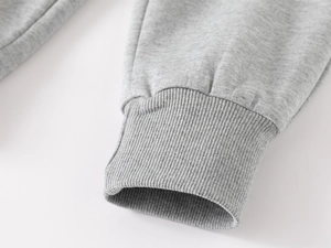 Détail du jogging gris montrant les poignets côtelés élastiques et la texture coton