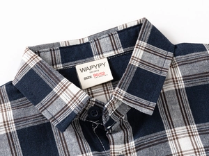 Close-up of classic plaid pattern collar and button on boys long sleeve shirt