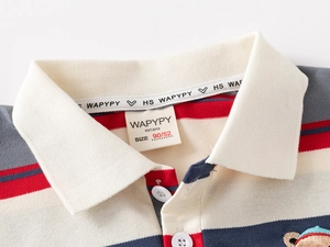 Détail macro du polo rayé pour enfant avec boutons et étiquette de col de marque