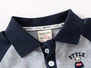 Detail of baby boy polo shirt with bear embroidery and contrast navy raglan sleeves