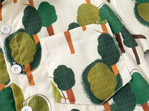 Detail of boys cotton shirt with forest print, front pocket and white buttons