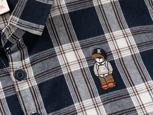 Detailed close-up of navy plaid shirt fabric with premium bear embroidery and tag