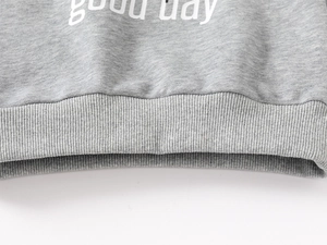 Detail of grey cotton sweatshirt ribbed hem with white 'good day' printed text